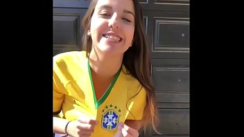 Очень горячая молодая девушка в коротких шортах, одетая в футболку сборной Бразилии