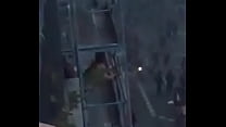 Une femme fudendo sur le balcon de l'immeuble pendant que des Français se manifestent