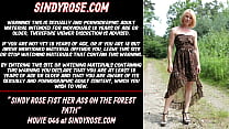 Sindy Rose com o punho cerrado no caminho da floresta