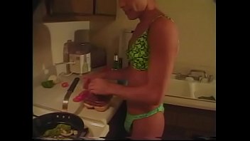 Gay bronzeado em lingerie prepara o jantar na cozinha enquanto seu amigo fode ele no cuzinho