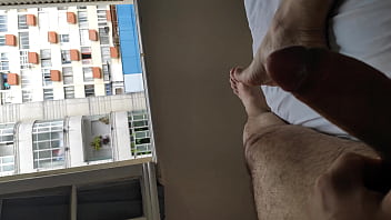 Vollständige nackte Masturbation mit gespreizten Beinen vor vielen Fenstern