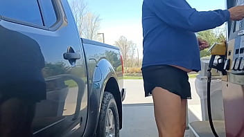 Un vieil homme prend de l'essence en jupe courte