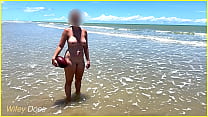 Femme nue à la plage publique se fait éclabousser d'eau
