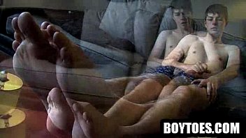 Stud shows his feet and tugs on his cock on the couch